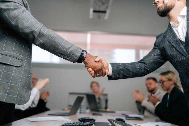 Two business professionals shaking hands in a meeting, suggesting agreements and understanding on licensing costs.